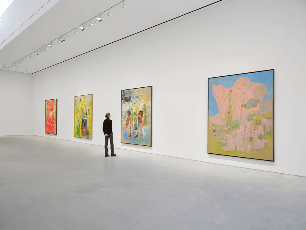 A gallery visitor viewing paintings in a white exhibition space